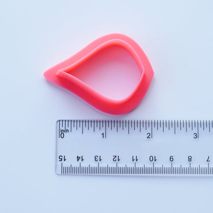 Pink pear shaped clay cutter is shown above a ruler that measures 1.75 inch.
